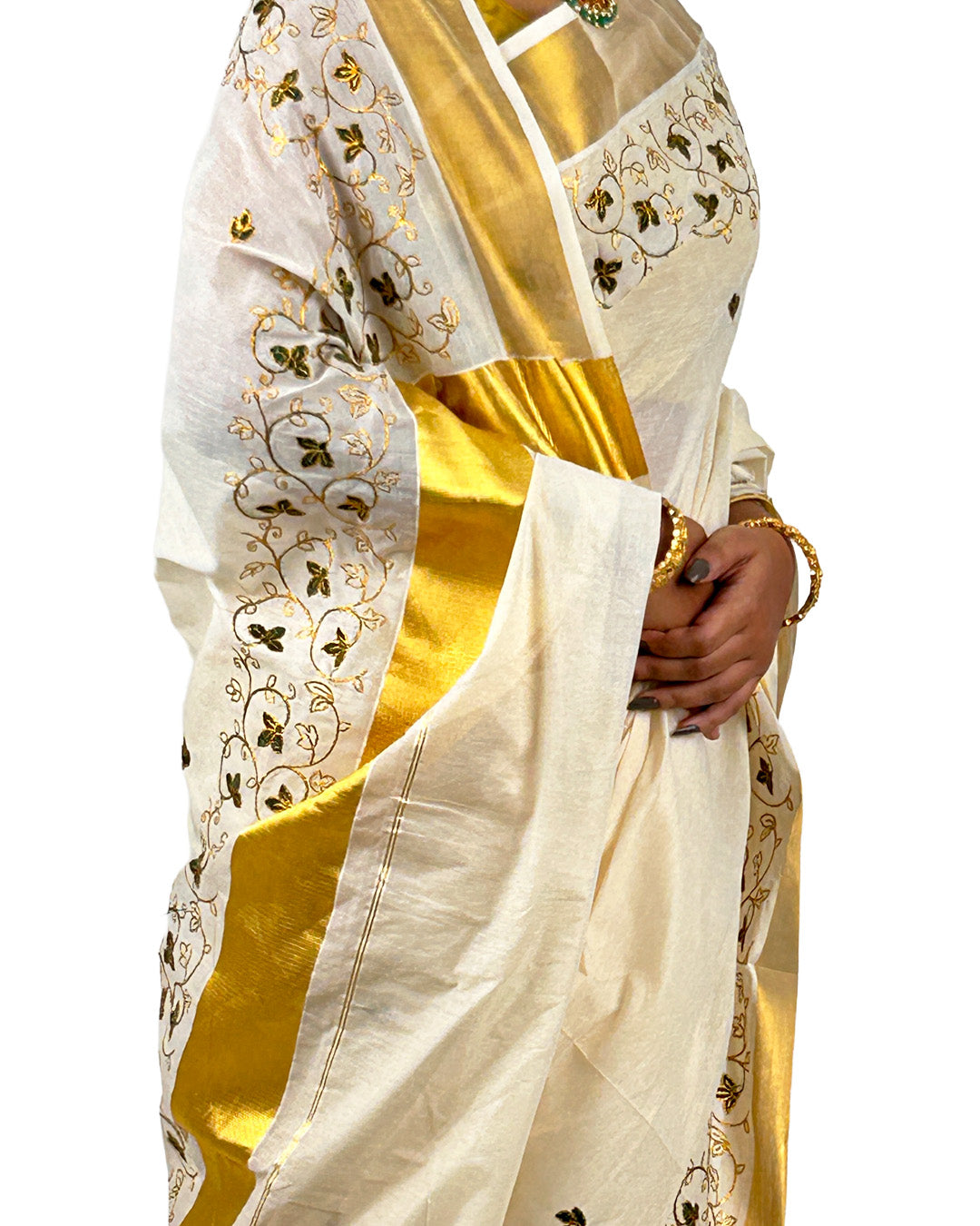 White Kasavu saree with gold and green embroidery patterns held by a hand on a white background