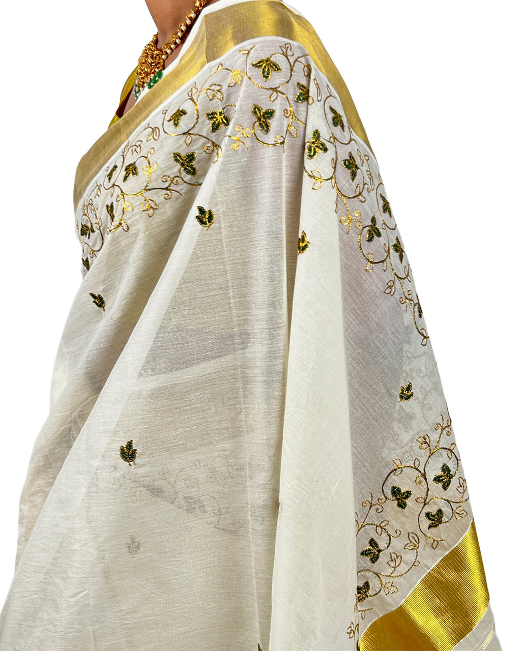 White saree with gold and green embroidery on a white background