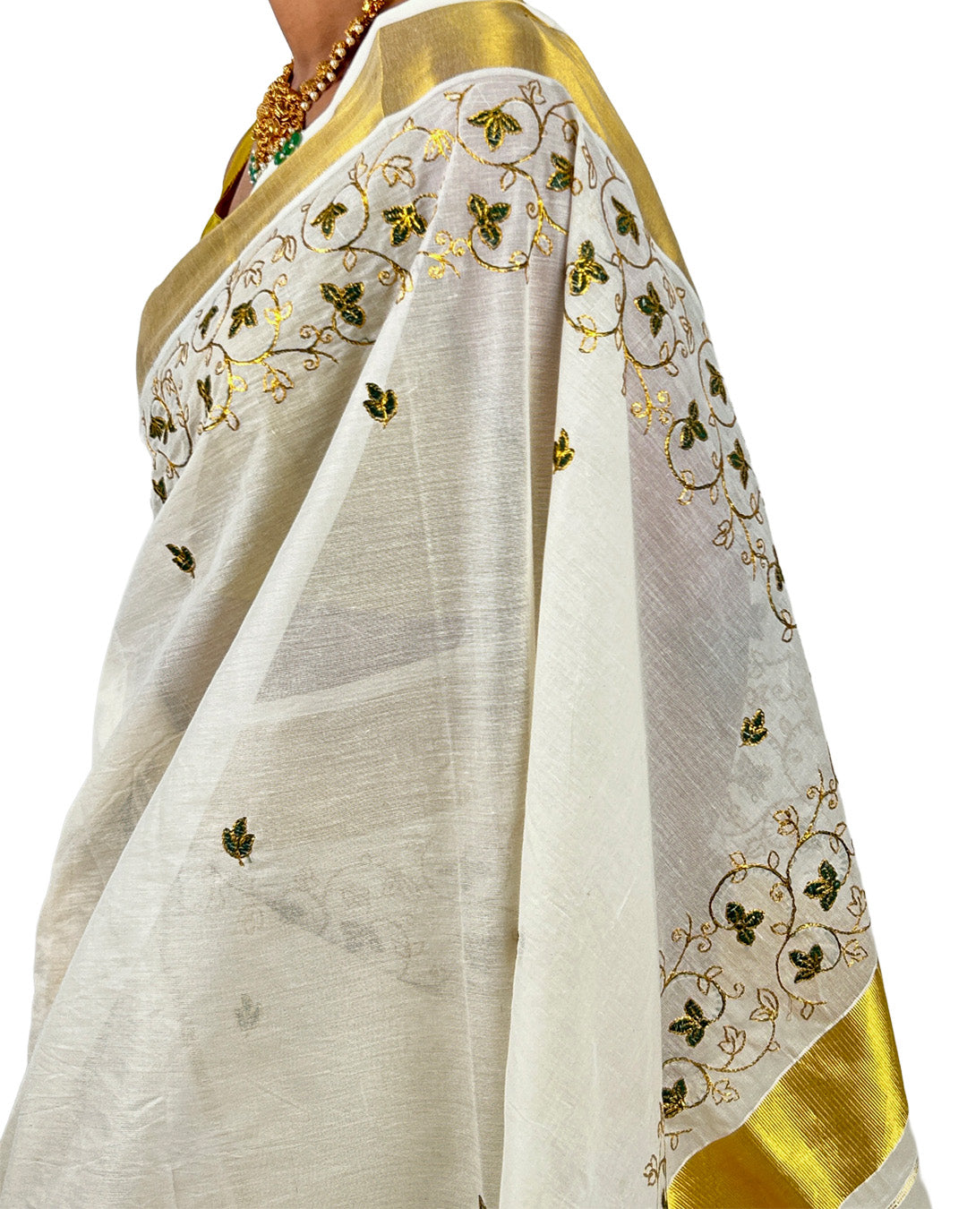 White saree with gold and green embroidery on a white background