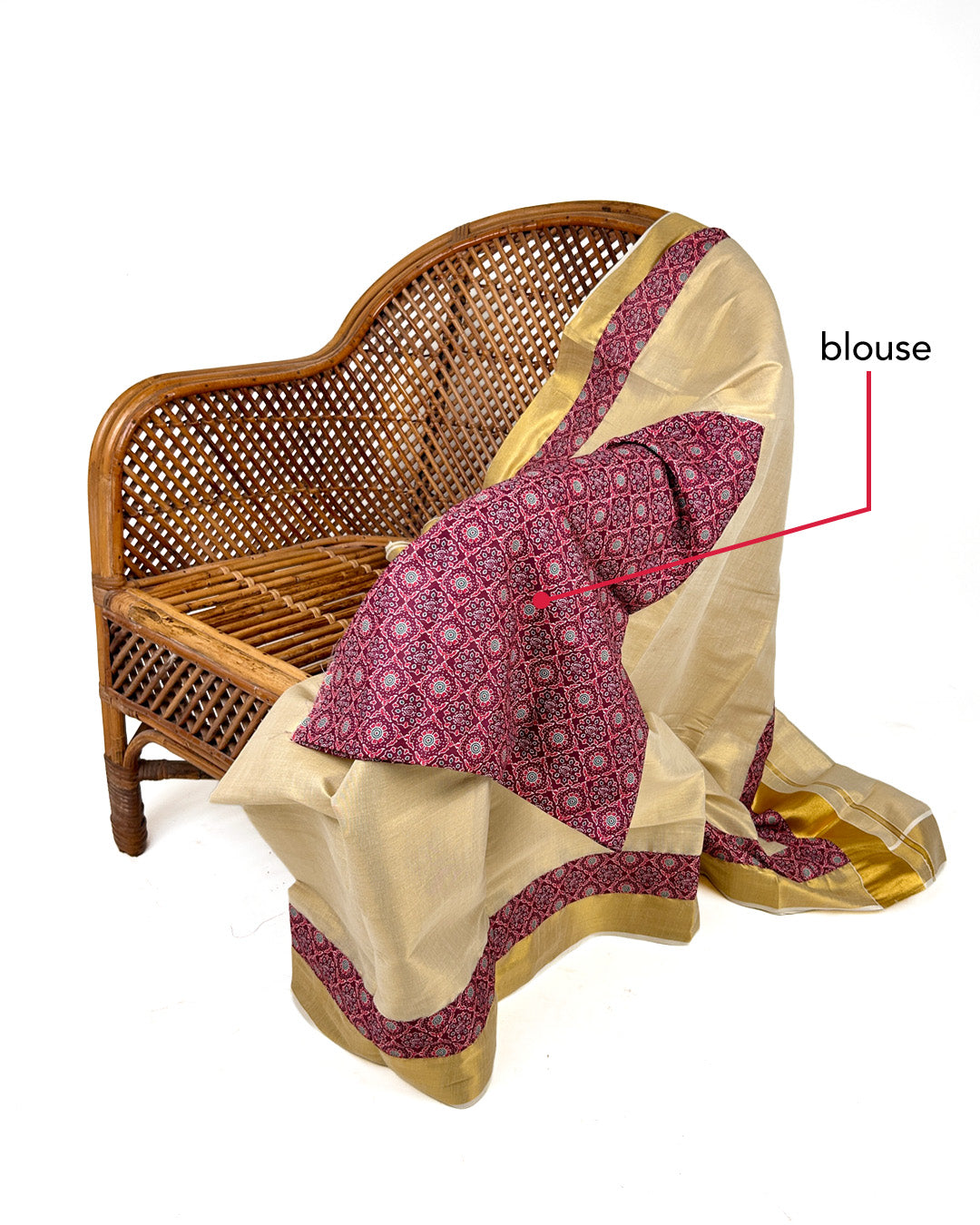 Sari with blouse draped over a wicker chair on a white background