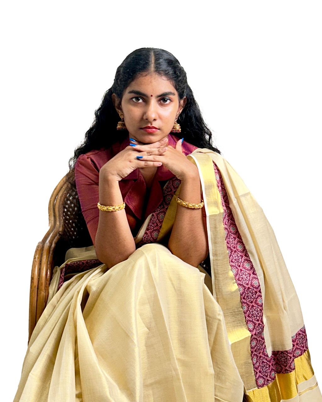 Woman wearing a traditional Kerala kasavu saree with maroon border, styled with a maroon blouse — photographed on a white background. Perfect for Onam, weddings, and festive occasions.
